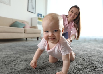 Photo of Adorable little baby crawling near mother at home