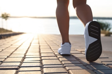 Young woman running near river in morning, closeup. Space for text