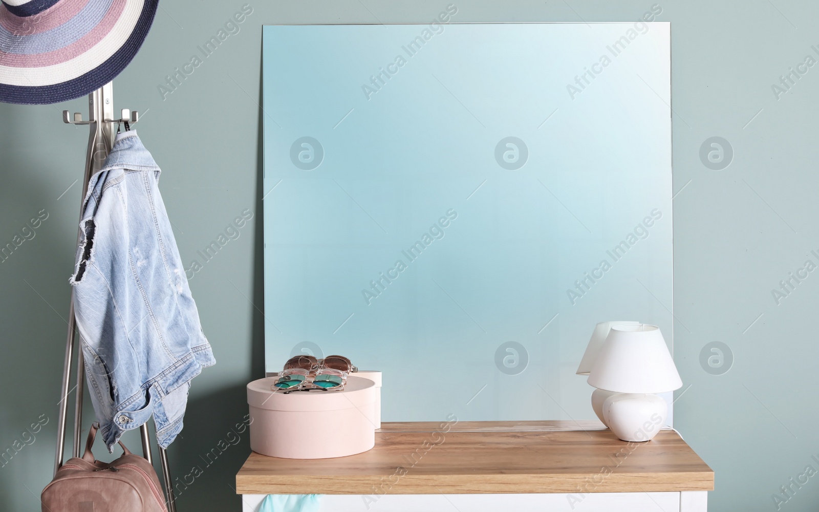 Photo of Modern mirror on commode near light wall
