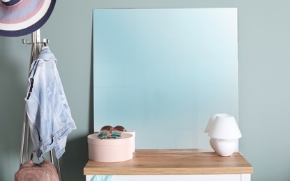 Modern mirror on commode near light wall