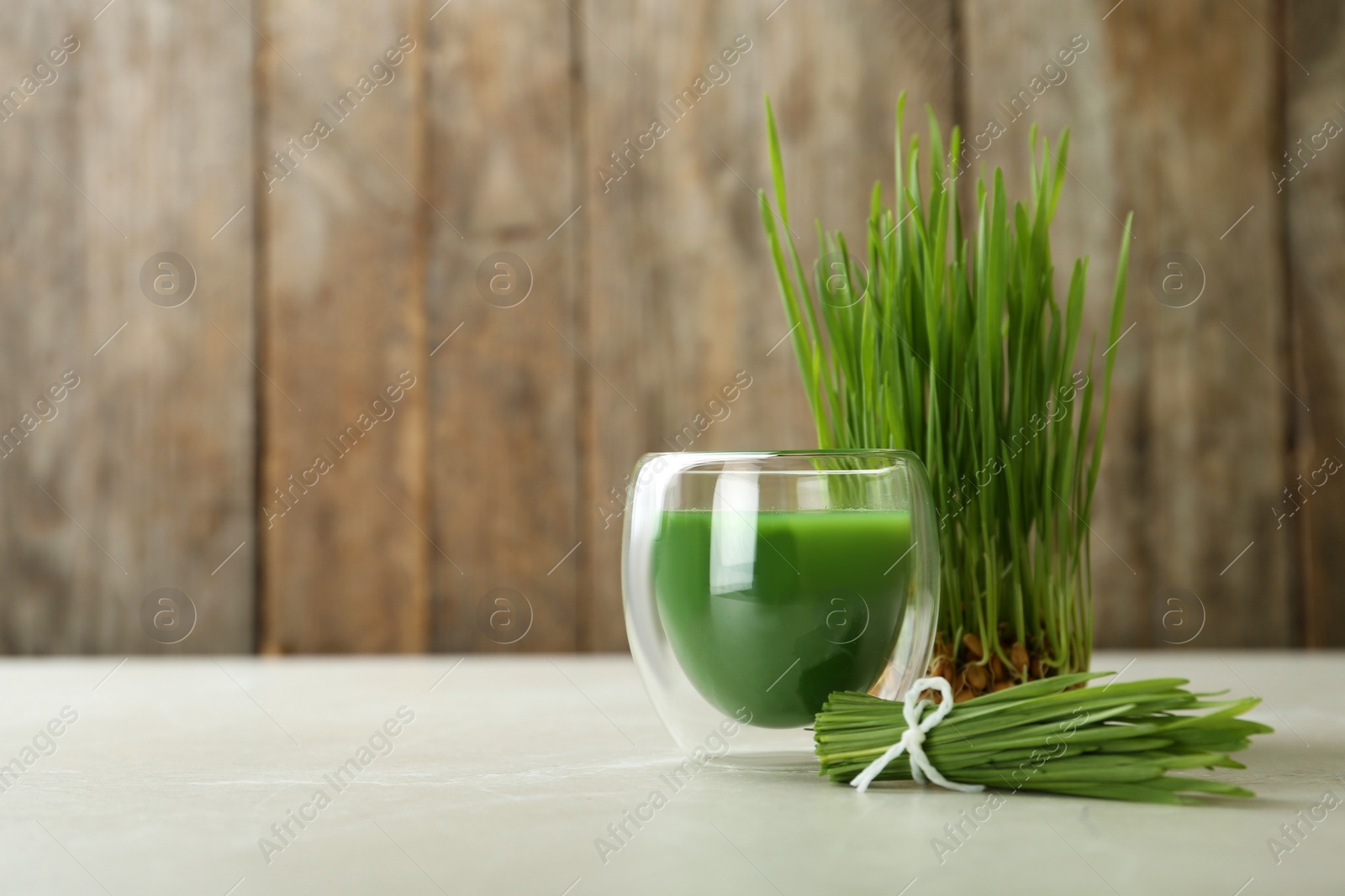 Glass of wheat grass juice and sprouts on table. Space for text Photo of Glass of wheat grass juice and sprouts on table. Space for text