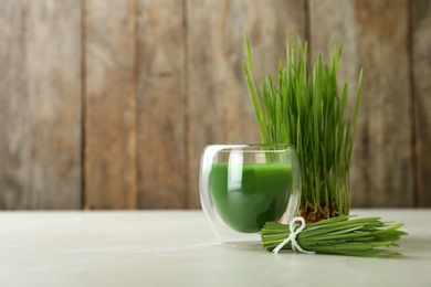 Photo of Glass of wheat grass juice and sprouts on table. Space for text