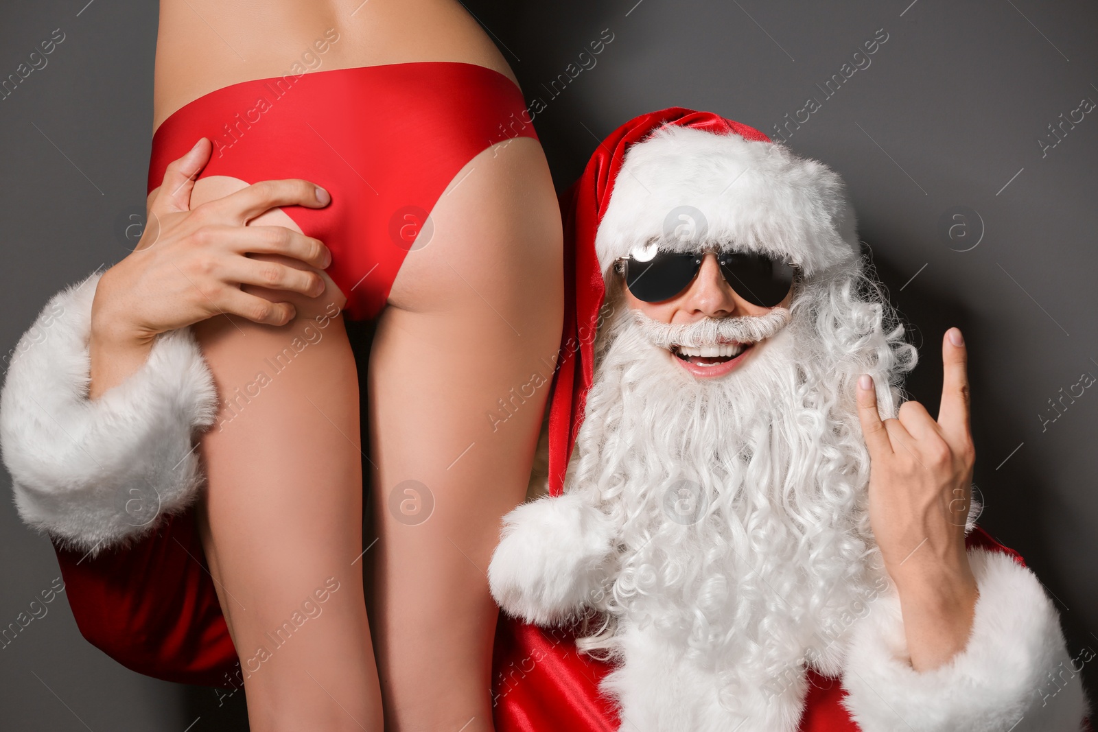 Photo of Young Santa Claus with sexy naked woman on dark background