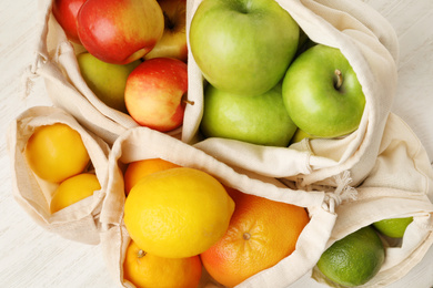 Photo of Cotton eco bags with fruits, closeup view