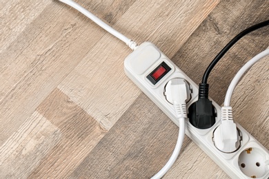 Extension cord on wooden floor, top view with space for text. Electrician's equipment