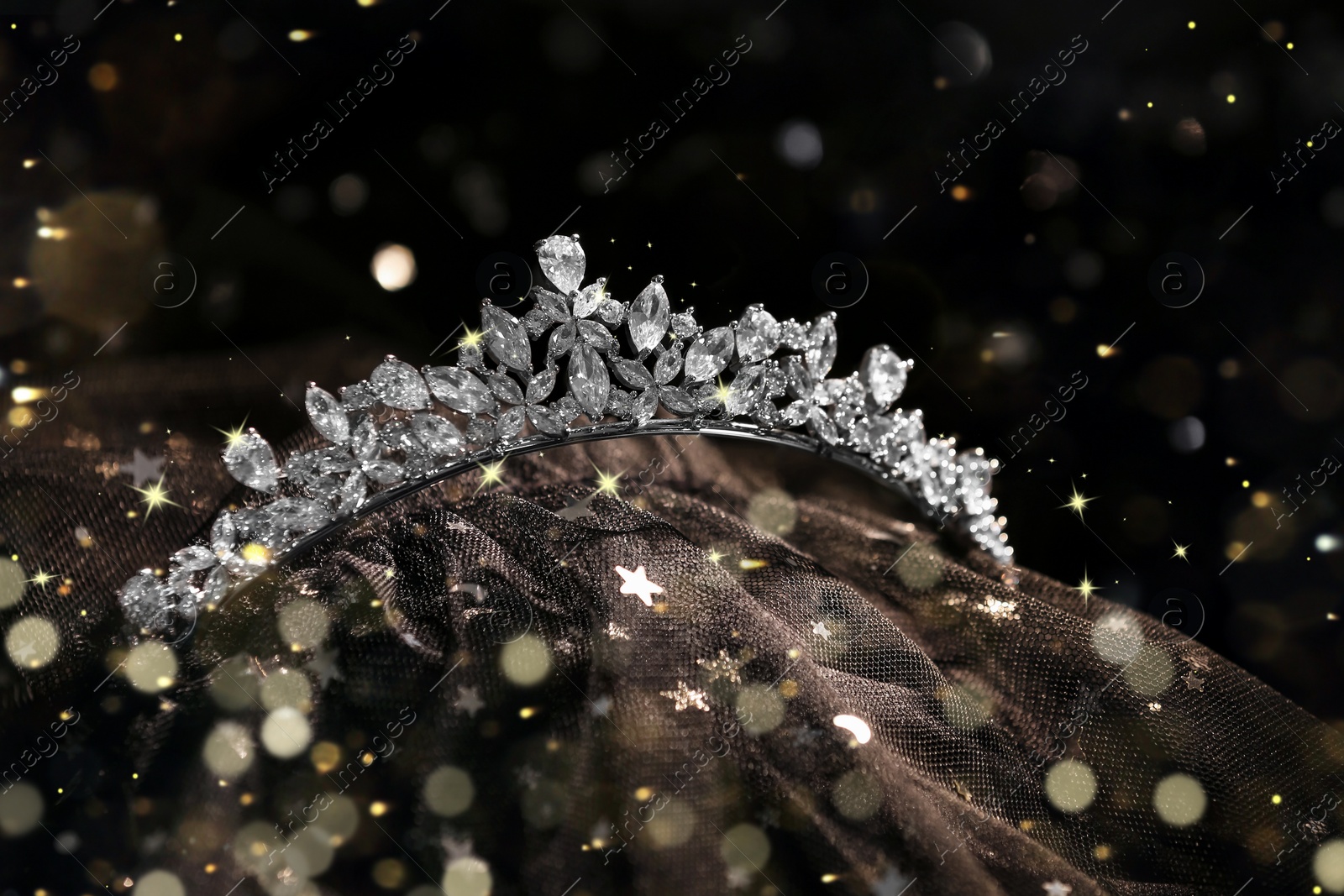 Image of Beautiful silver tiara with diamonds on black cloth, bokeh effect