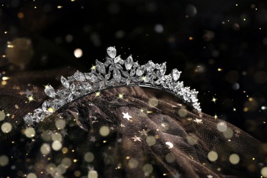 Beautiful silver tiara with diamonds on black cloth, bokeh effect