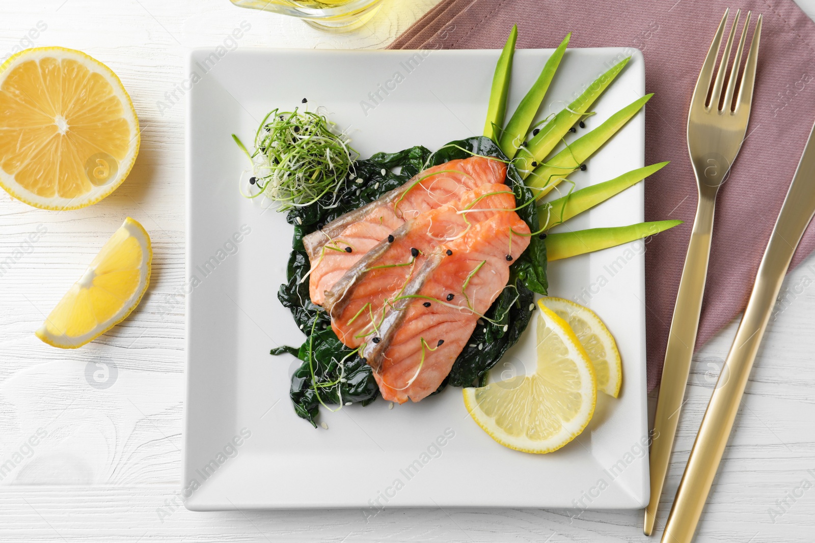 Photo of Tasty salmon with spinach served on white wooden table, flat lay