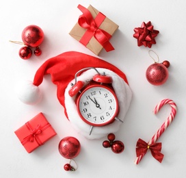 Flat lay composition with alarm clock and Christmas decor on white background. New Year countdown