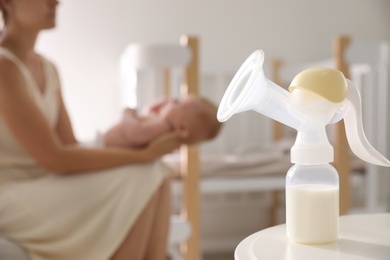 Photo of Mother and little baby indoors, focus on table with breast pump