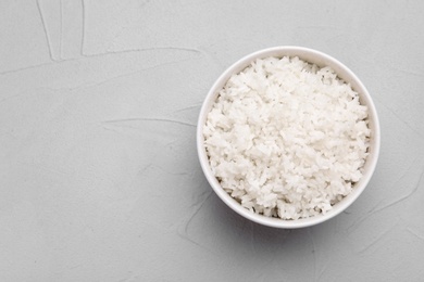 Photo of Bowl of boiled rice on color background, top view with space for text