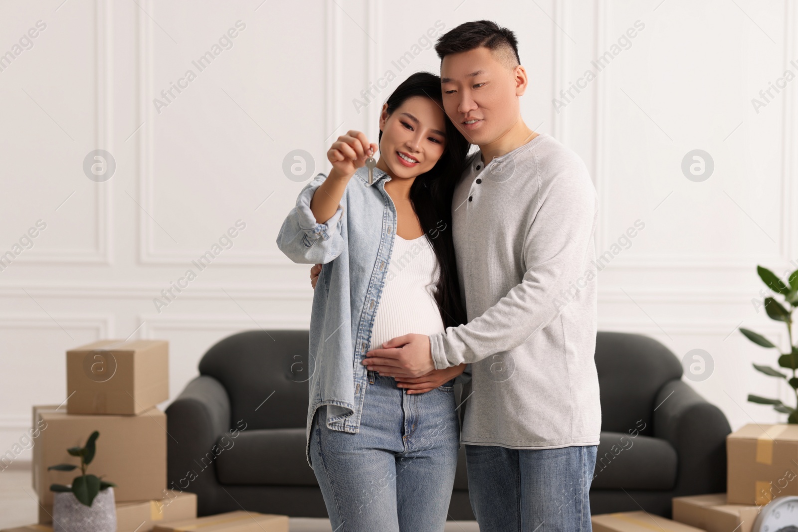 Photo of Pregnant woman and her husband with key in their new apartment