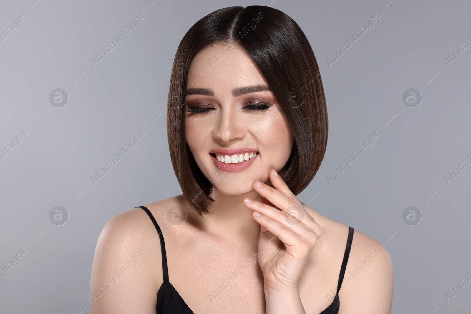 Image of Portrait of pretty young woman with brown hair smiling on grey background