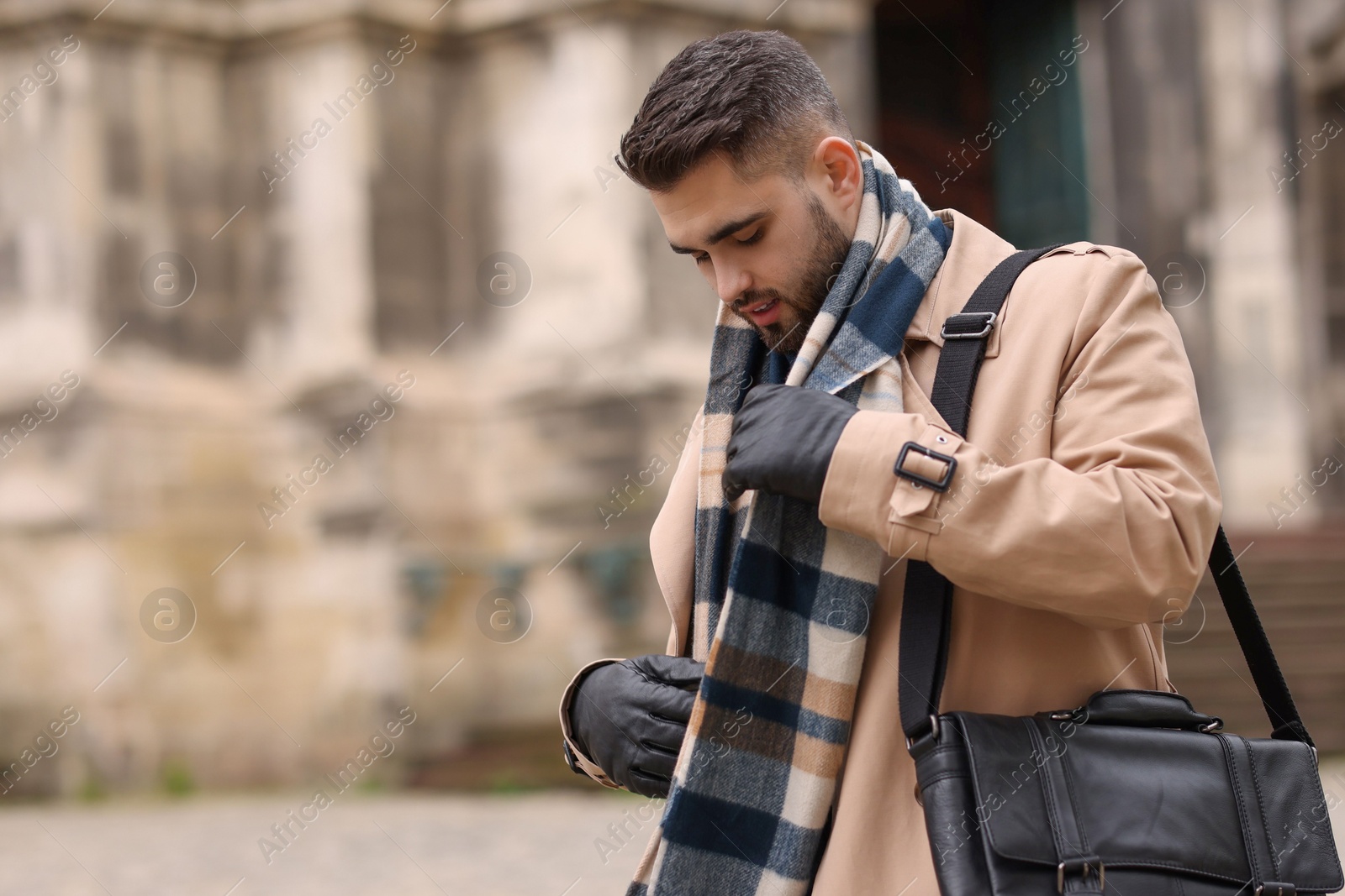 Photo of Handsome man in warm scarf outdoors. Space for text