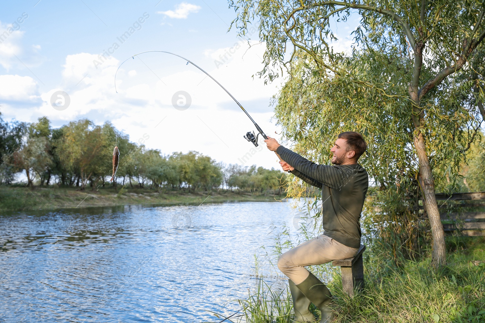 Photo of Man with rod fishing at riverside. Recreational activity