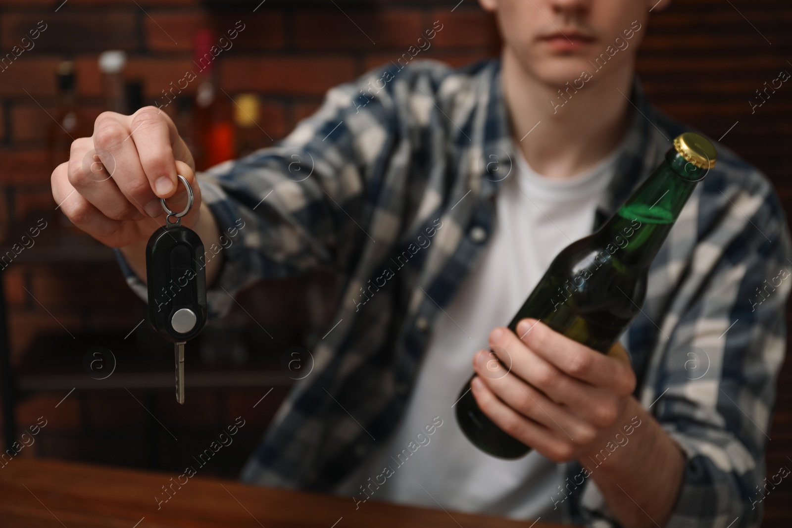 Photo of Man with bottle of beer and car keys in bar, closeup. Don't drink and drive concept