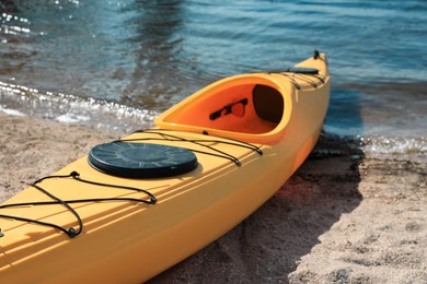 Photo of Yellow kayak on beach near river. Summer camp activity