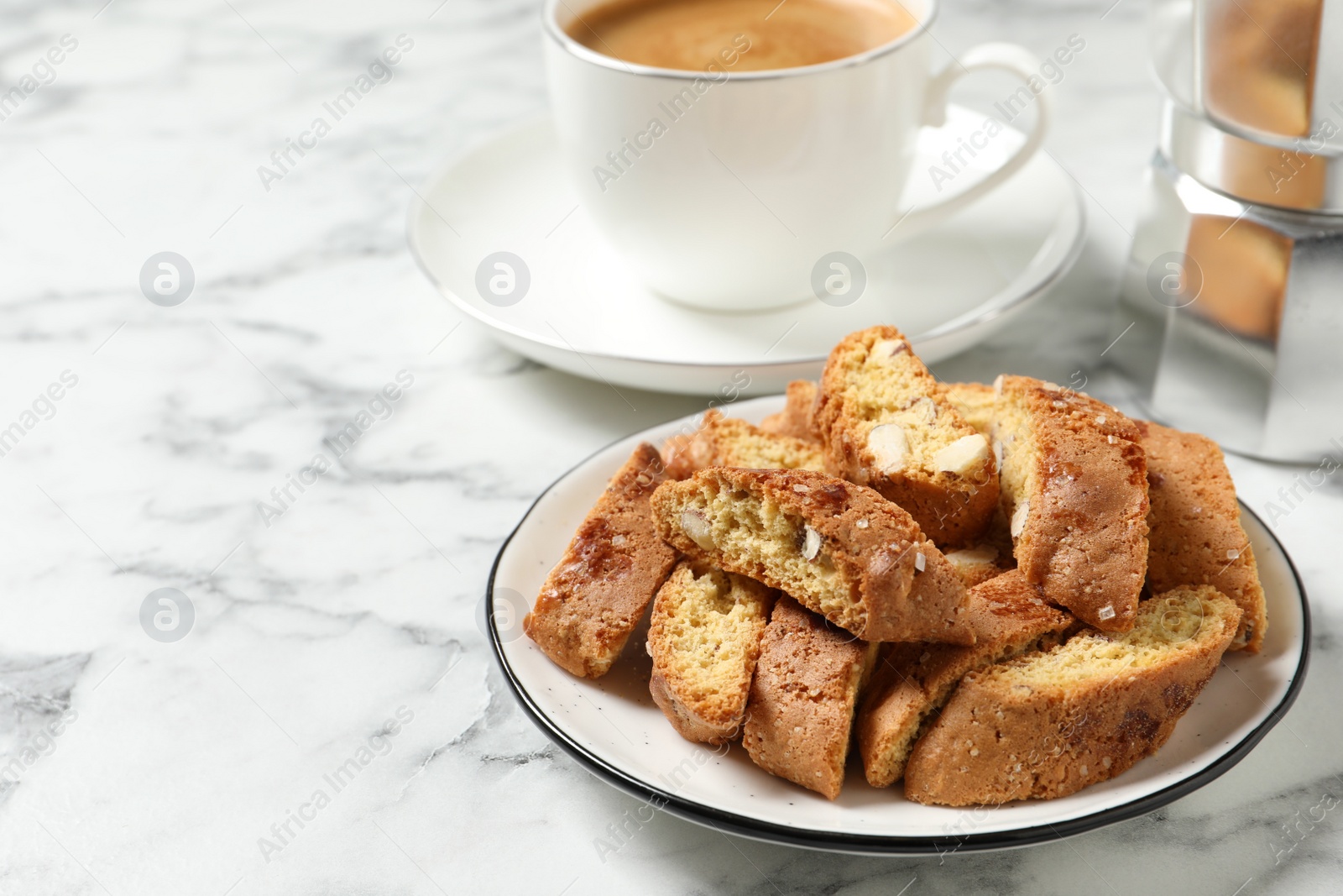 Photo of Tasty cantucci and cup of aromatic coffee on white marble table, space for text. Traditional Italian almond biscuits