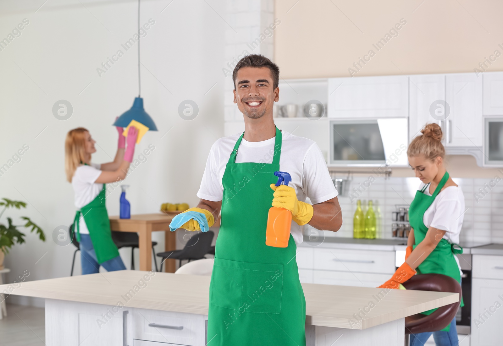 Photo of Team of professional janitors in uniform cleaning kitchen