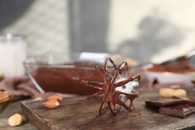 Whisk with chocolate cream on table, closeup. Space for text