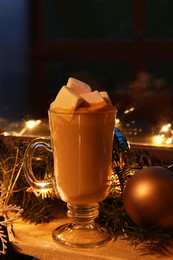 Photo of Glass of delicious hot cocoa with marshmallows and Christmas decoration on windowsill