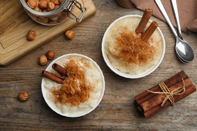 Delicious rice pudding with cinnamon on wooden table, flat lay