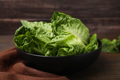 Photo of Bowl of fresh green romaine lettuces on wooden table, closeup