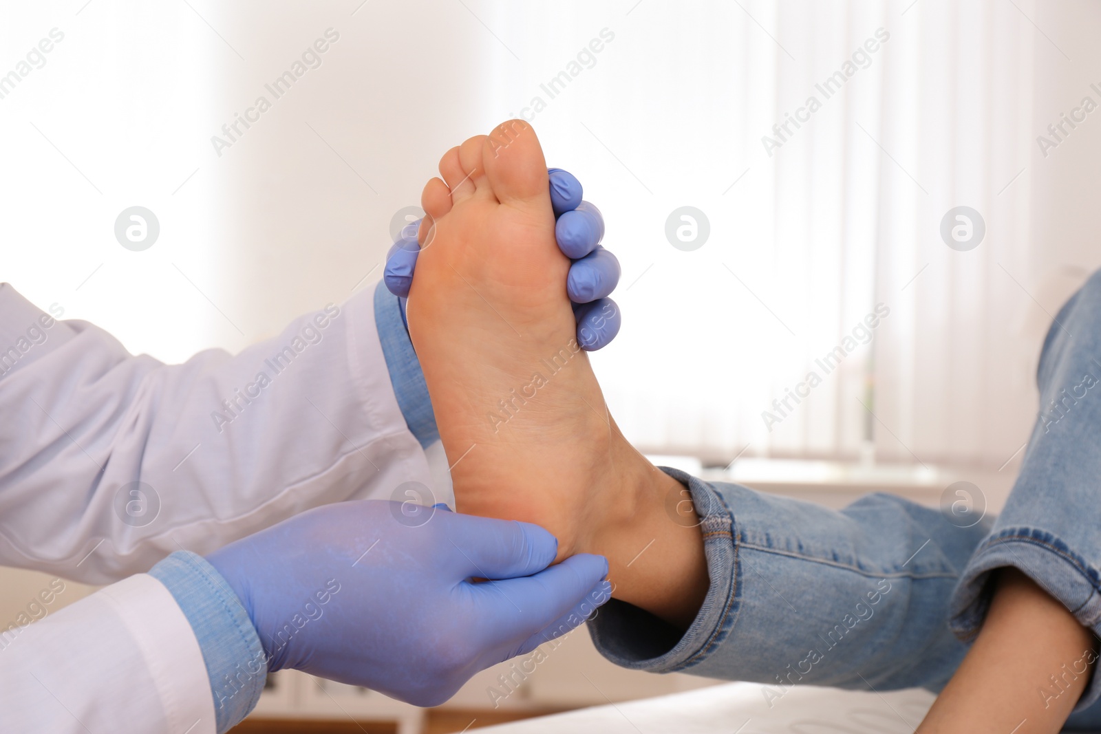 Photo of Male orthopedist checking patient's foot in clinic, closeup