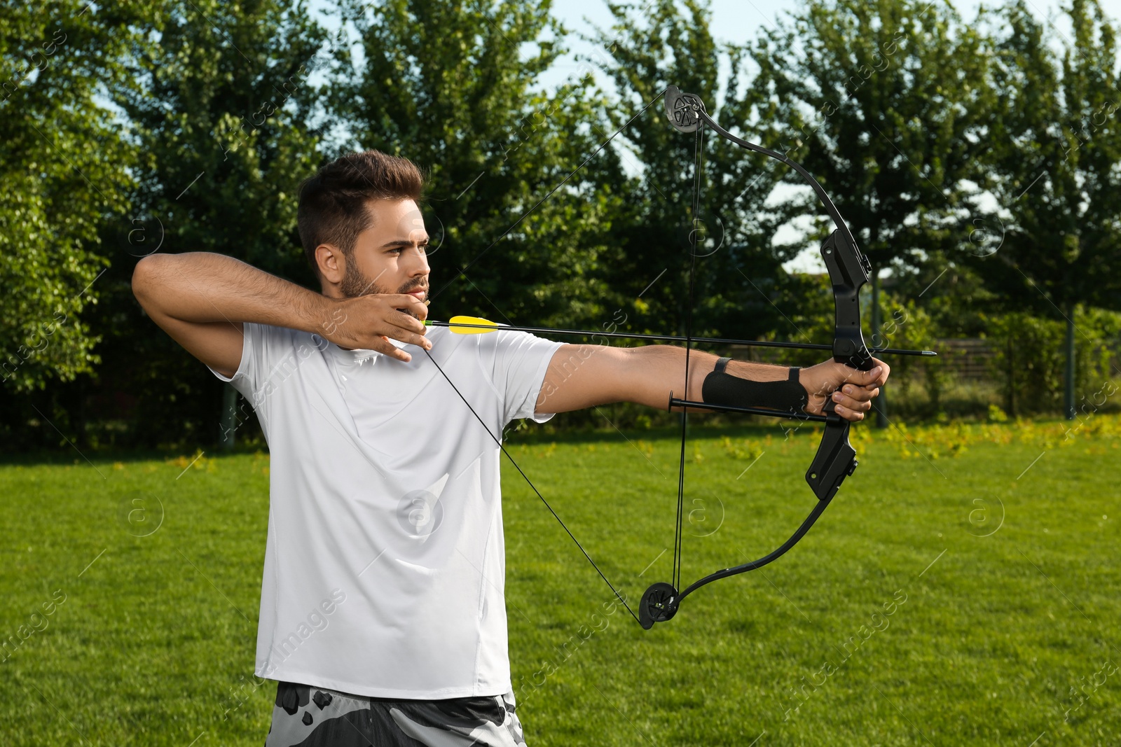 Photo of Man with bow and arrow practicing archery in park