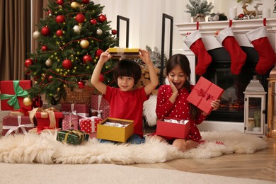 Photo of Cute children opening Christmas gifts on floor at home