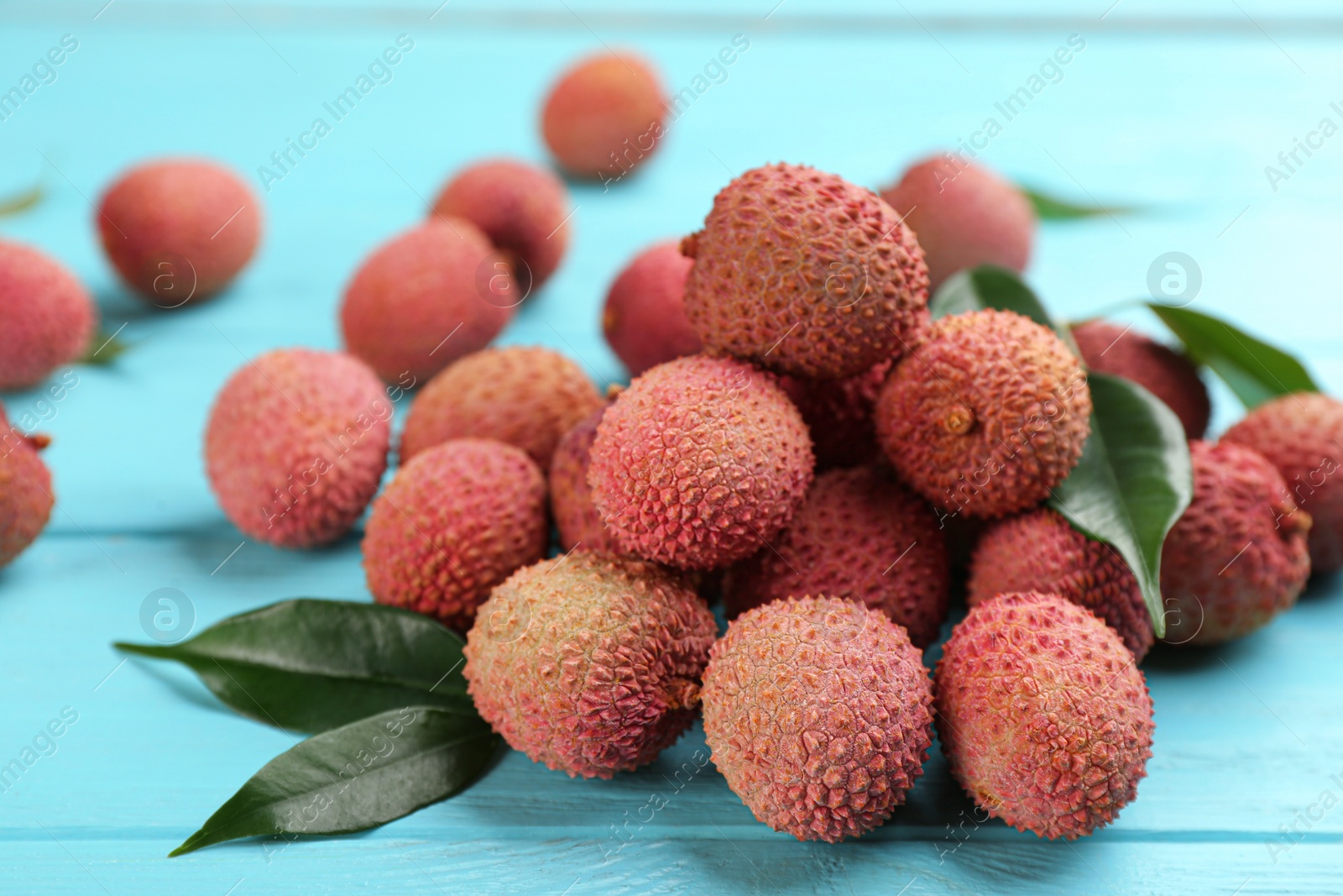 Photo of Fresh ripe lychee fruits on light blue wooden table