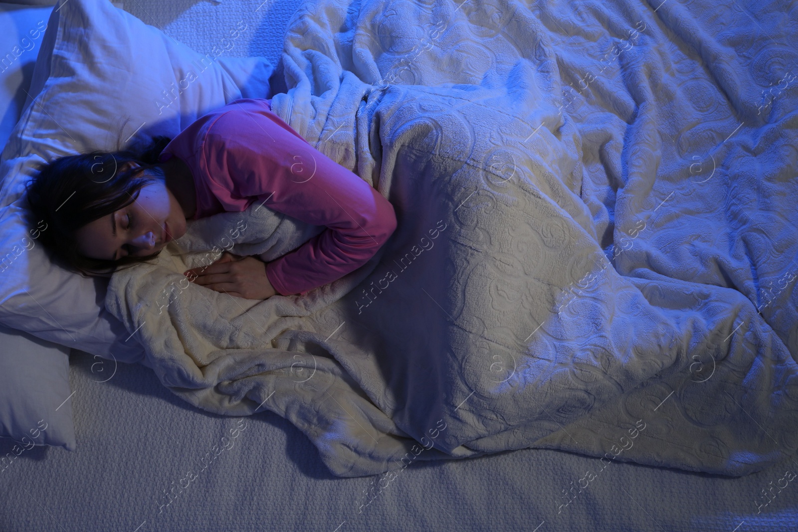 Photo of Young woman sleeping in soft bed at night, above view