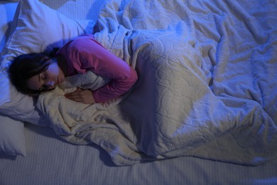 Young woman sleeping in soft bed at night, above view