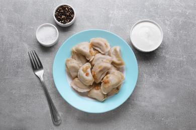 Photo of Delicious dumplings (varenyky) with potatoes and onion served on grey table, flat lay