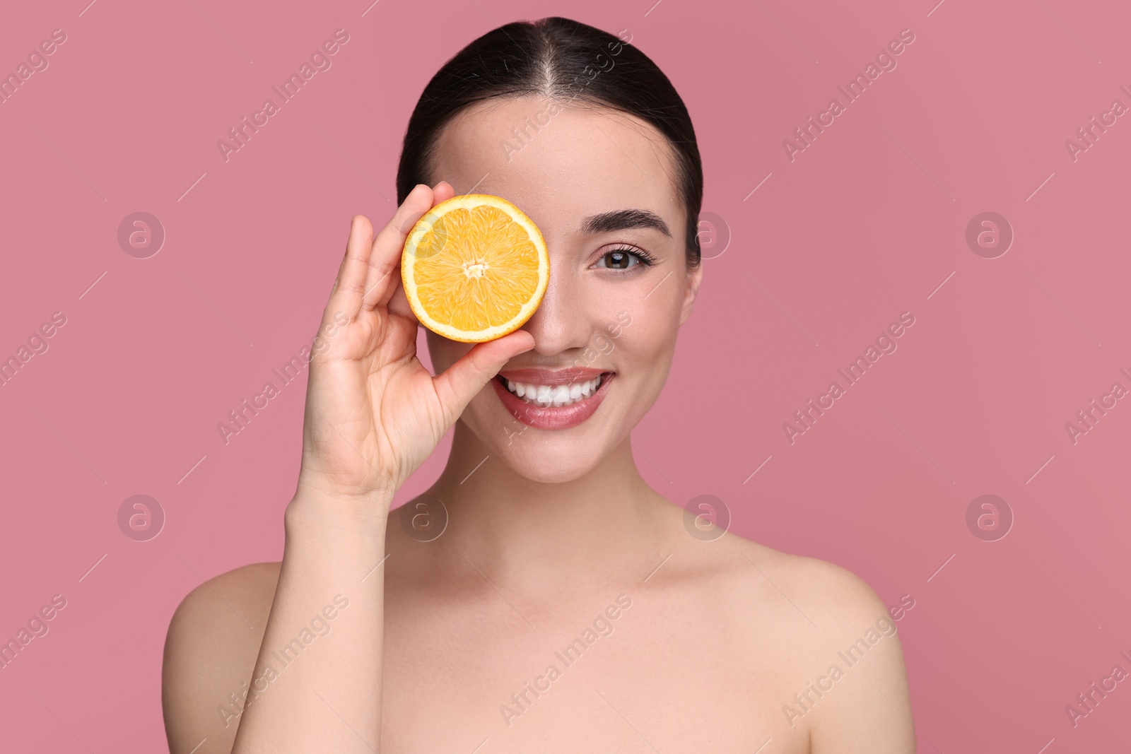 Photo of Beautiful young woman with piece of orange on pink background