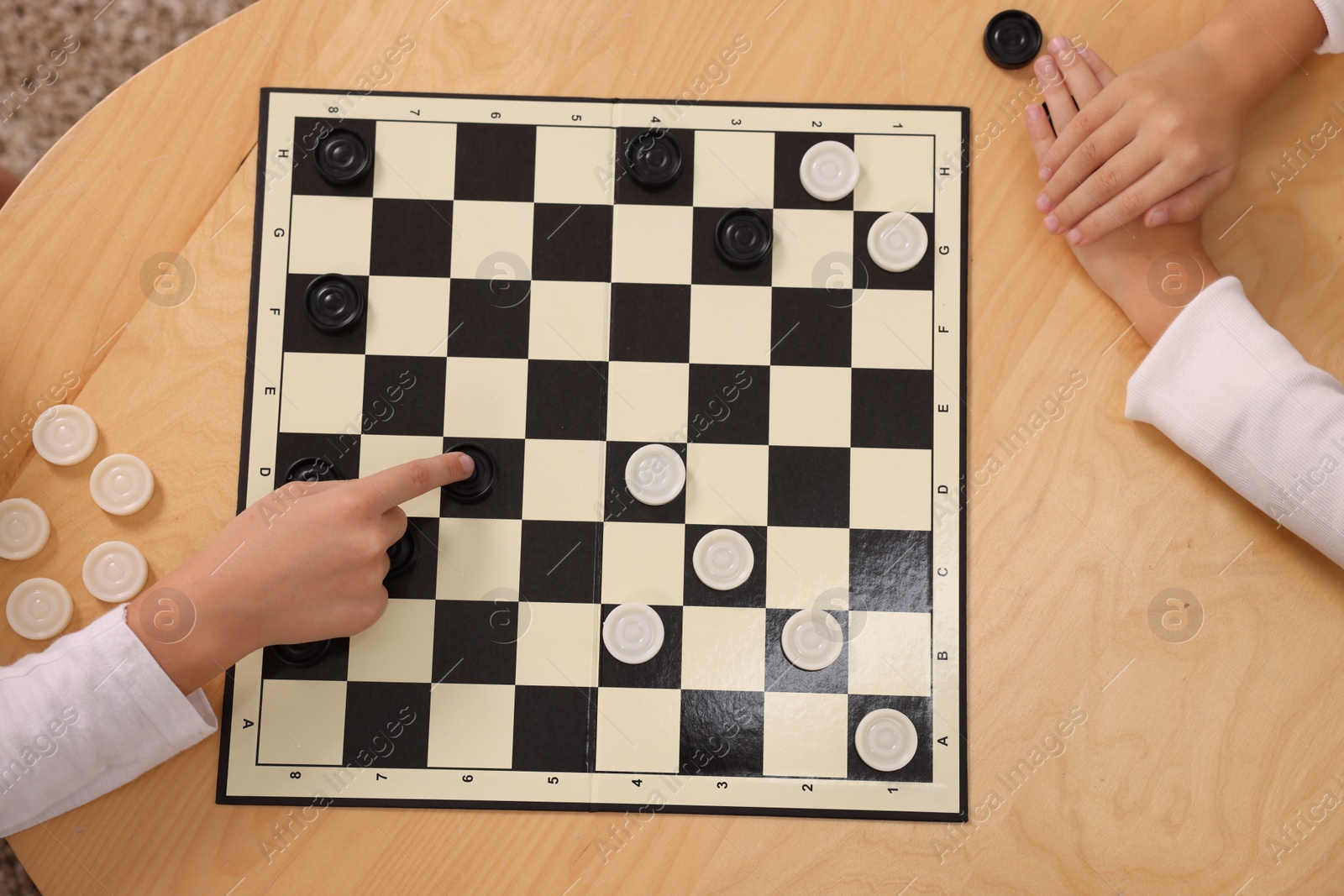 Photo of Children playing checkers at coffee table, top view