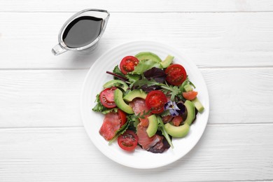Tasty soy sauce and plate of salad on white wooden table, flat lay