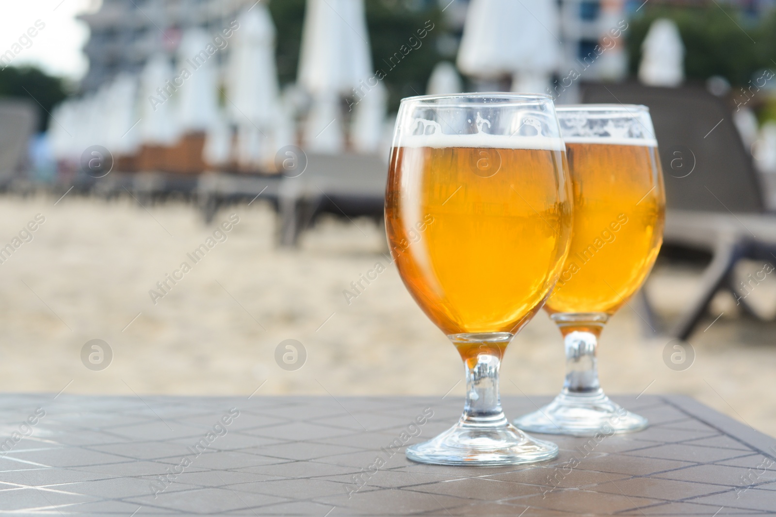 Photo of Cold beer in glass on beach. Space for text