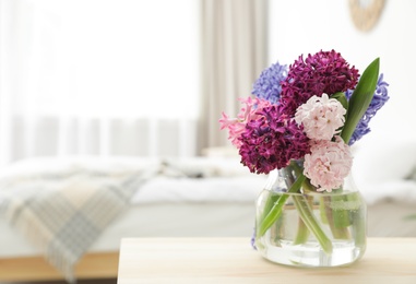 Photo of Beautiful hyacinths in glass vase on table indoors, space for text. Spring flowers