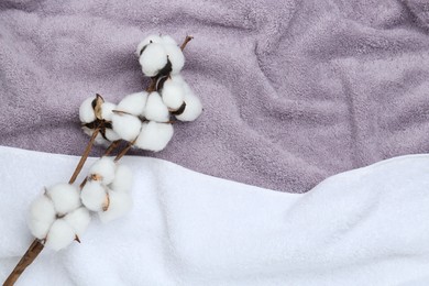 Photo of Cotton flowers on terry towels, top view. Space for text