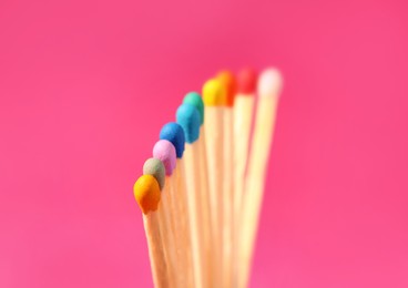 Photo of Matches with colorful heads on pink background, closeup