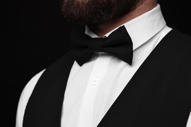 Photo of Man in shirt and bow tie on black background, closeup