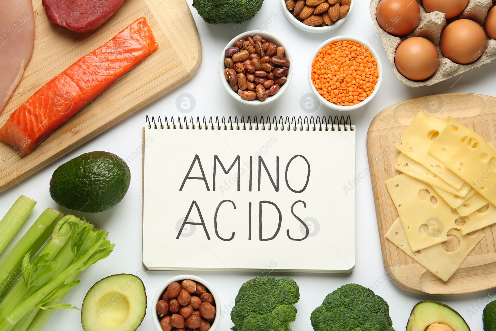 Photo of Different fresh products and notebook with words Amino Acids on white background, top view