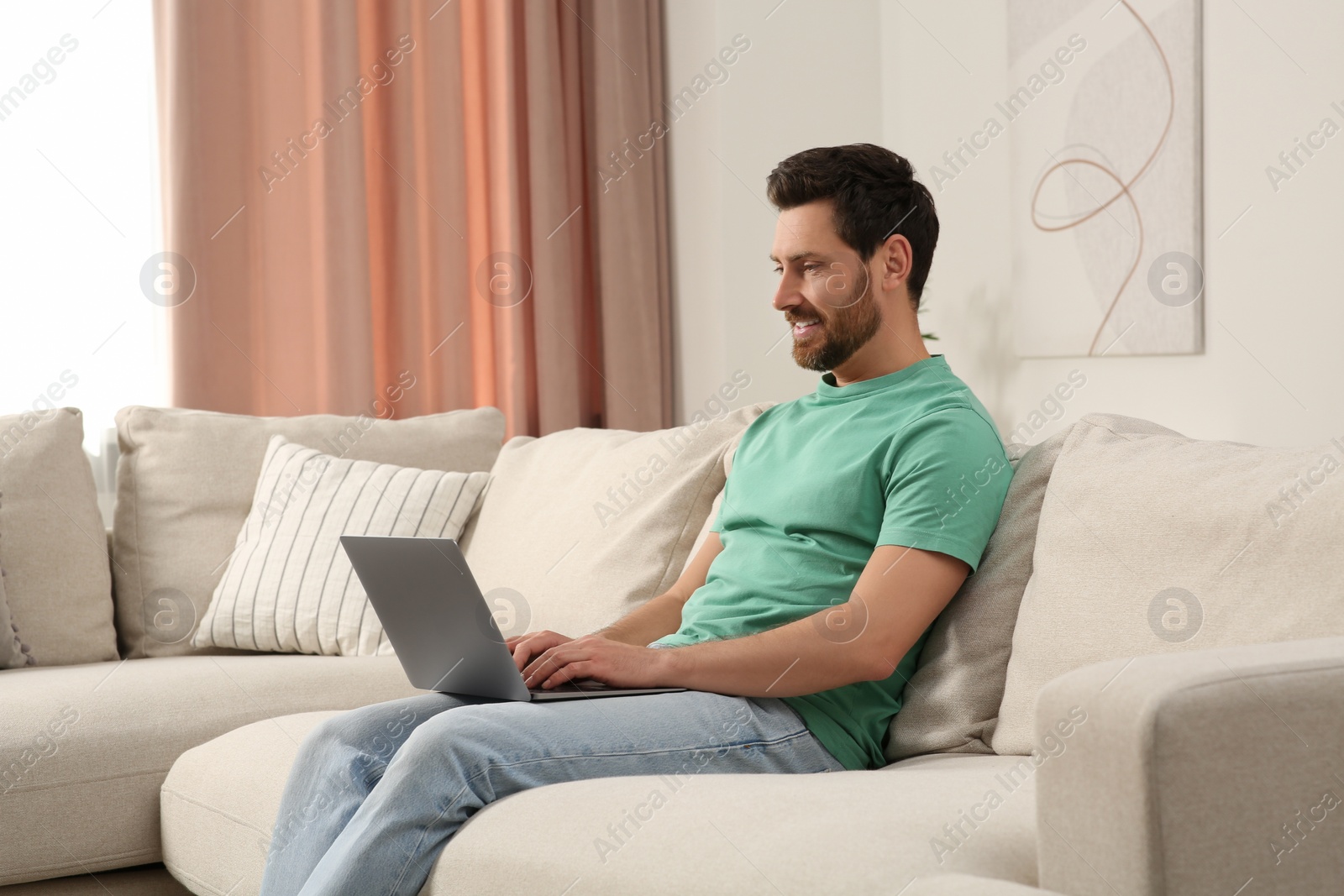 Photo of Man using laptop on sofa at home