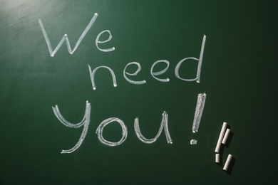 Phrase "We need you" written on green chalkboard, top view. Plea for help