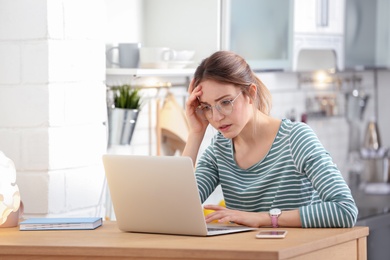 Troubled young woman working on laptop at home