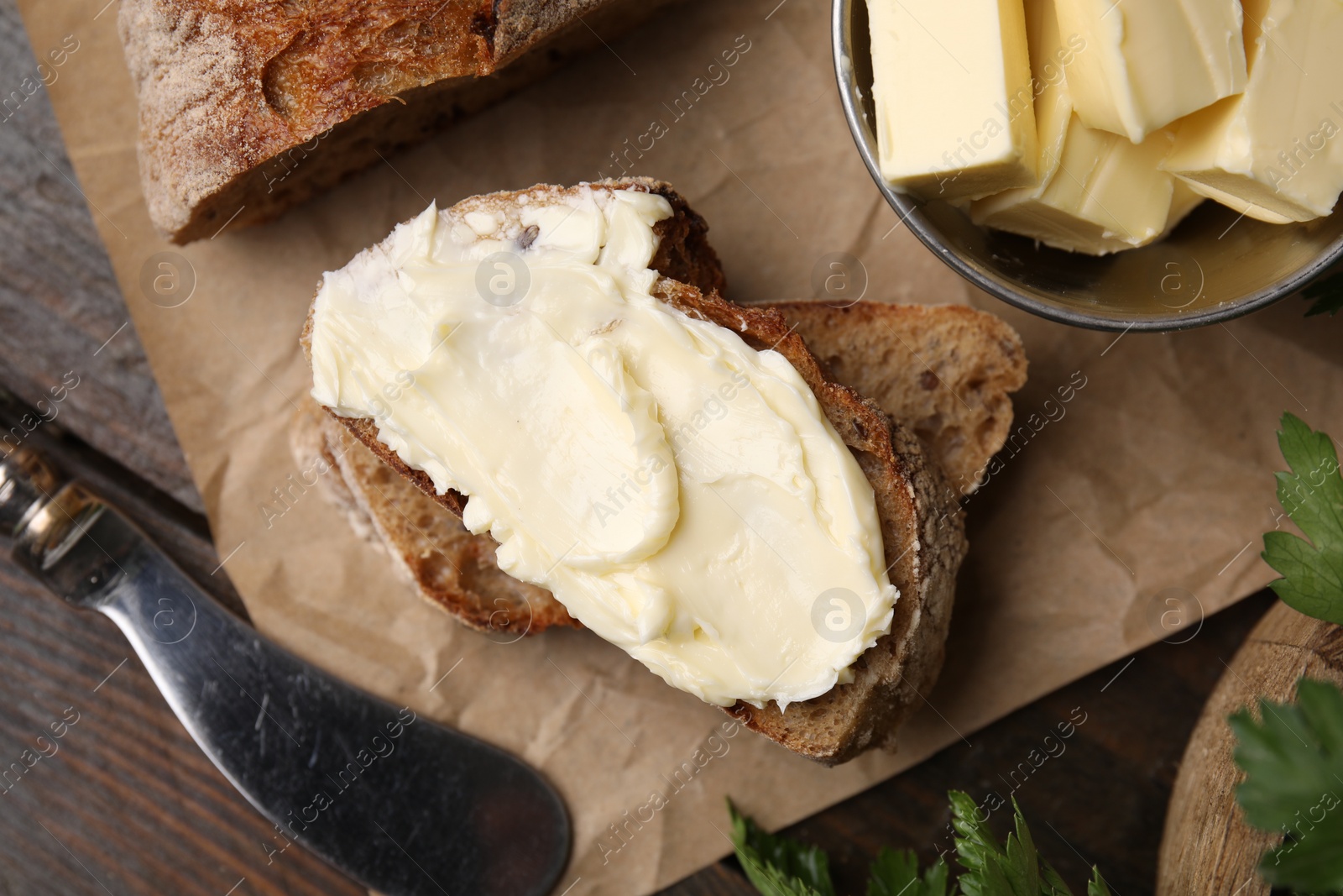 Photo of Tasty bread with butter and knife on table, flat lay