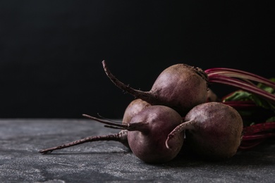 Photo of Fresh beets on grey table against black background. Space for text