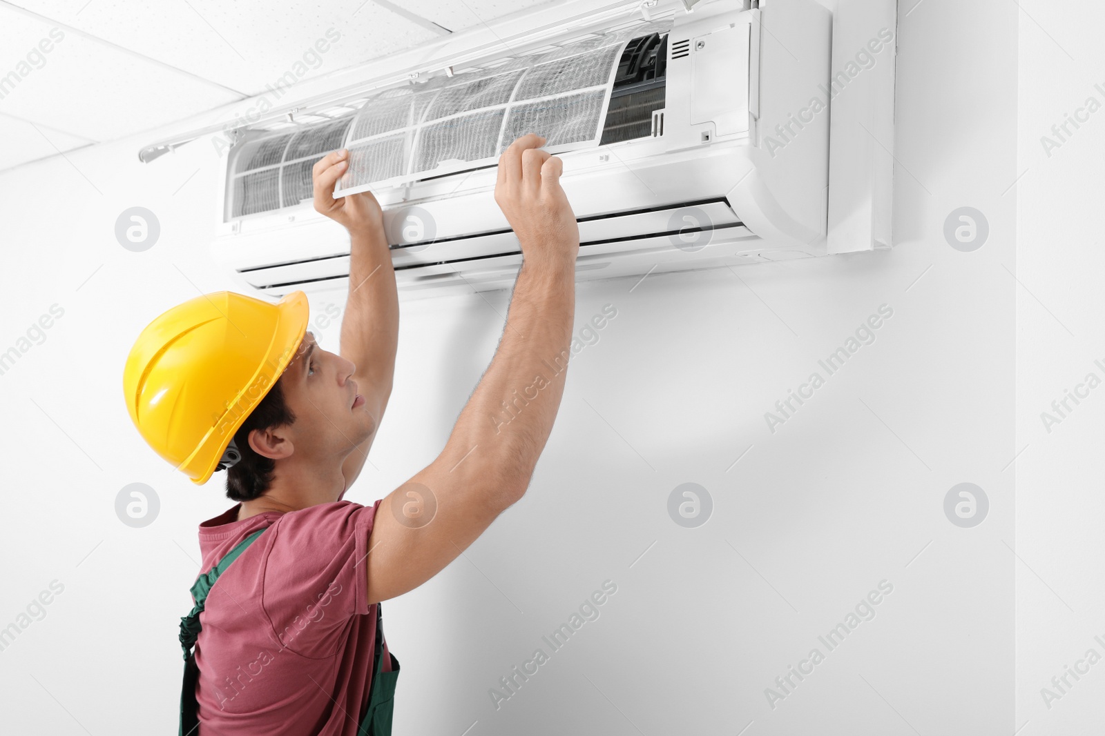 Photo of Male technician cleaning air conditioner indoors