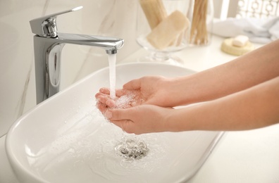 Photo of Woman washing hands indoors, closeup. Bathroom interior